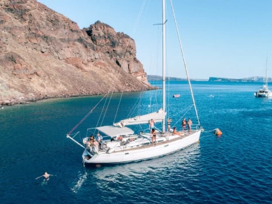 Samboat boat rental: anchored white sailboat by rocky cliffs with a swimmer nearby in a calm blue bay